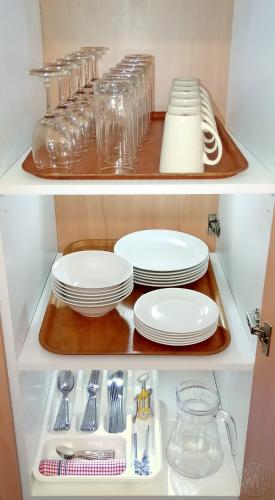 two shelves of a kitchen with plates and utensils at Millicent Motel in Millicent