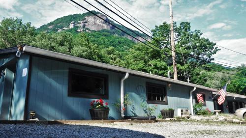 a blue building with a mountain in the background at Riverside Lodge at Chimney Rock in Chimney Rock
