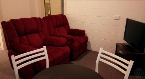 a living room with a red couch and two chairs at Millicent Motel in Millicent