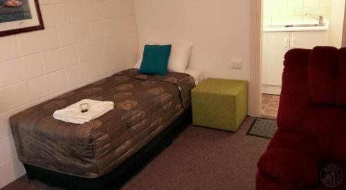 a small room with two beds and a green ottoman at Millicent Motel in Millicent