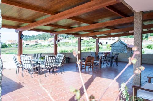 a patio with chairs and tables and a wooden ceiling at Casa Codesal Apartamentos in Noalla