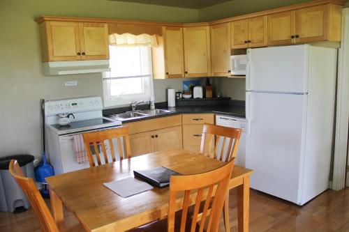 Una cocina con una mesa de madera y un refrigerador blanco. en Swept Away Cottages, en Cavendish