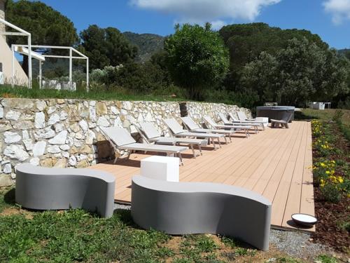 a row of benches sitting next to a stone wall at Poggio di Sole in Lacona