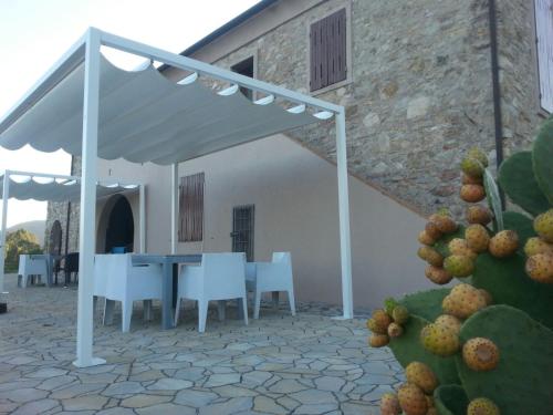 a patio with a table and chairs under a white umbrella at Poggio di Sole in Lacona