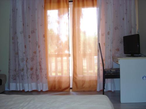um quarto com duas janelas com cortinas e uma televisão em Apartman Darja em Umag