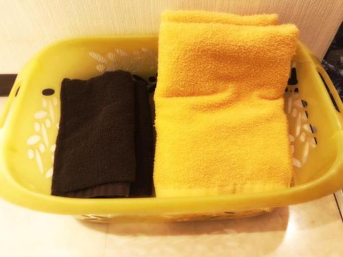 a yellow basket with two towels in it at Hotel Maganda (Adult Only) in Osaka