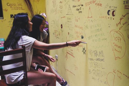 two women sitting in a chair writing on a wall at Tupac Lima Airport in Lima