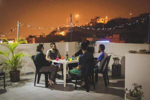 a group of people sitting at a table on a rooftop at night at Tupac Lima Airport in Lima