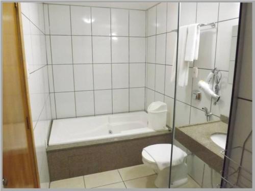 a bathroom with a tub and a toilet and a sink at Cometa Plaza Hotel in São Luiz Gonzaga