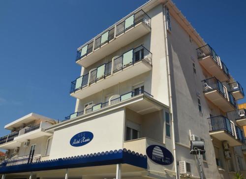 a tall white building with a blue sign on it at Hotel Karin in Rimini