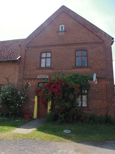a brick house with a bush with red flowers at Biogut Evensen in Evensen