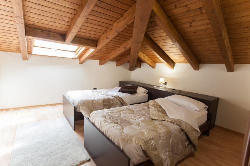 two beds in a room with wooden ceilings at AcquaTerraFuoco - City apartments in Como