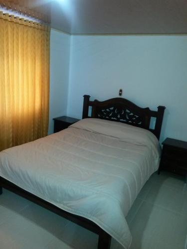 a bedroom with a large bed with white sheets at Hospedaje El Mirador in Iza