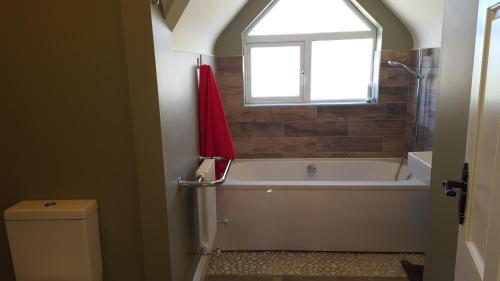 bagno con vasca, finestra e servizi igienici di Our Holiday Home a Enniscrone