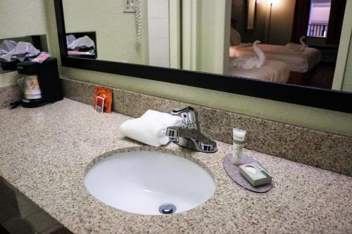 a bathroom counter with a sink and a mirror at Suite Dreams Hotel in Mattoon