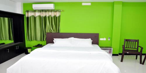 Un dormitorio verde con una cama blanca y una silla. en Sara Regency, en Palani