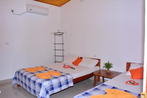 2 Betten in einem Zimmer mit orangefarbenen Handtüchern darauf in der Unterkunft Pleasant Park Holiday Inn in Trincomalee