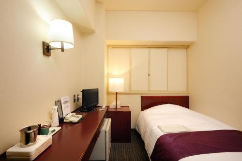 a hotel room with a bed and a desk with a computer at Ueda Plaza Hotel in Ueda