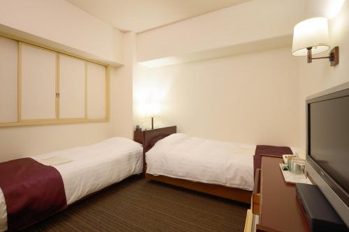 a hotel room with two beds and a flat screen tv at Ueda Plaza Hotel in Ueda