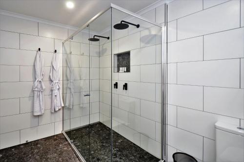 a bathroom with a shower with white tiled walls at Hotel Grand Chancellor Townsville in Townsville