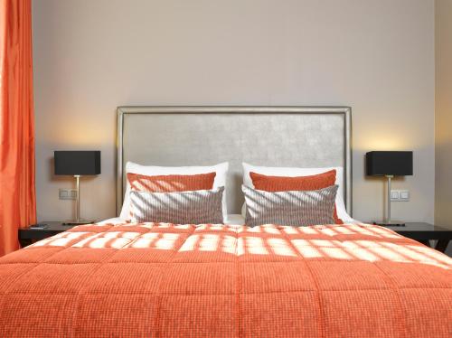 a bedroom with a bed with an orange blanket and pillows at Martin's Klooster in Leuven