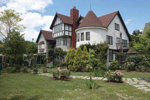 une grande maison avec un jardin en face de celle-ci dans l'établissement Petit Hotel & Restaurant Old Age, à Hokuto