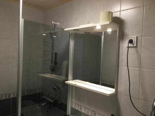 a bathroom with a shower with a mirror at Hotelli Salpa in Luumäki