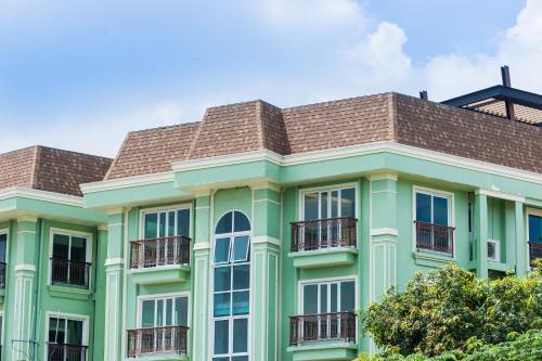 
a green building with a blue roof and windows at Dang Derm in The Park Khaosan - SHA Extra Plus in Bangkok
