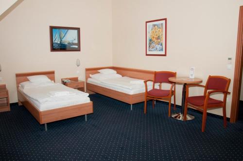a room with two beds and a table and chairs at Hotel Paprika in Hegyeshalom