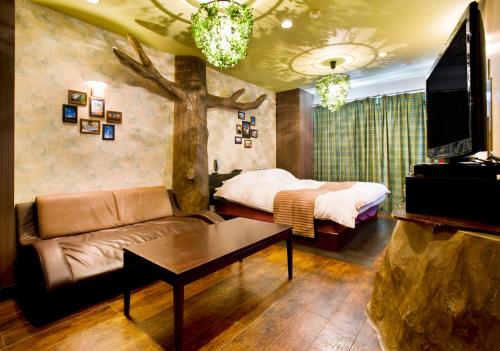 a living room with a couch and a bed at ホテルココナッツリゾートアミー Love Hotel in Kagoshima