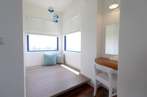 a small room with a desk and two windows at Zen Ocean in Jian