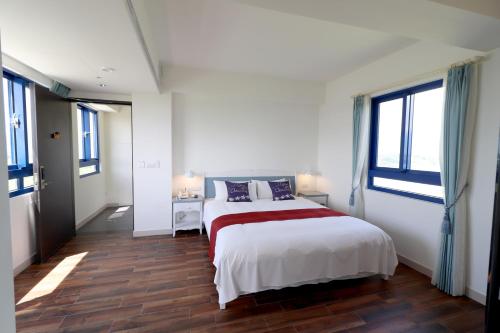 a white bedroom with a large bed and windows at Zen Ocean in Jian