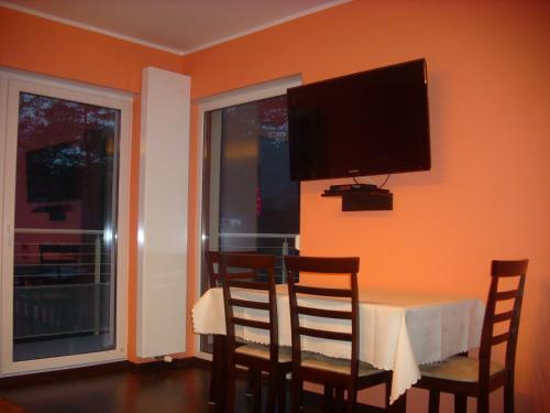 a dining room with a table and a television on the wall at Sonatka w Apartamentowcu Sonata in Międzywodzie
