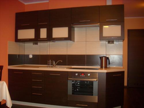 a kitchen with black cabinets and a sink and an oven at Sonatka w Apartamentowcu Sonata in Międzywodzie