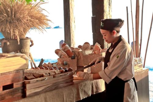 a woman is preparing food on a table at Buri Rasa Village Phangan in Thong Nai Pan Noi