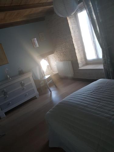 a bedroom with a bed and a dresser and two windows at Gite La Ptite Lazz in Les Riceys