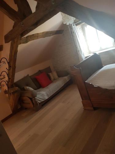 a room with a bed and a couch in a attic at Gite La Ptite Lazz in Les Riceys