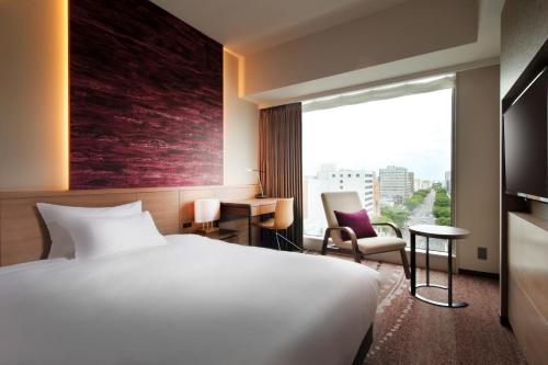 a hotel room with a bed and a large window at Hotel Metropolitan Sendai East in Sendai