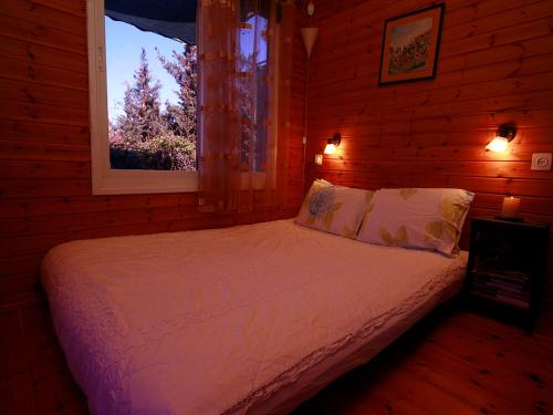 a bed in a wooden room with a window at Cabin In The View in Hararit