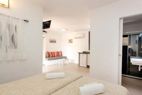 Habitación blanca con cama y sala de estar. en Bungalows Sa Sargantana, en Playa de Migjorn