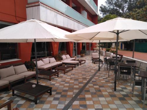 a patio with couches and umbrellas and tables and chairs at Hotel Spa Pinar del Mar in Platja  d'Aro