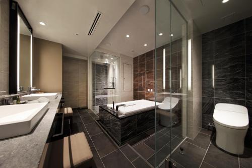 a bathroom with two sinks and a shower and a toilet at Hotel Metropolitan Sendai East in Sendai