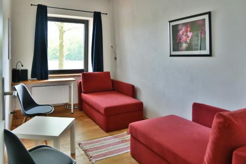 a living room with a red couch and a chair at Seehaus Hartwigsdorf in Klein Vielen