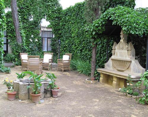a garden with a bench and chairs and plants at Palacio de la Rambla in Úbeda