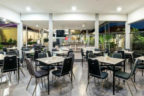un restaurante con mesas, sillas y ventanas en Riverstone Hotel & Cottage, en Batu