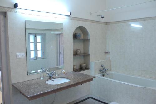 uma casa de banho com um lavatório, uma banheira e um espelho. em Brijraj Bhawan Palace Hotel em Kota