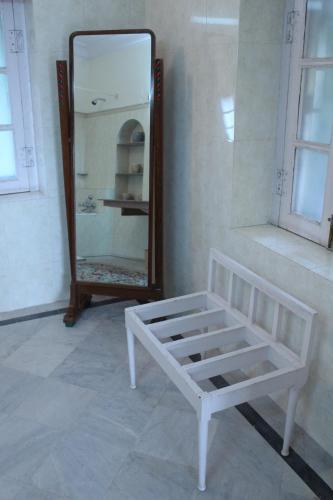 a white bed and a mirror in a room at Brijraj Bhawan Palace Hotel in Kota