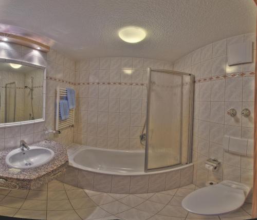 a bathroom with a shower and a sink and a tub at Gasthof Kienberg in Inzell