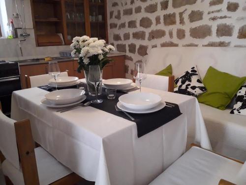 a table with a white table cloth and a vase of flowers at Holiday Home Mara in Tisno