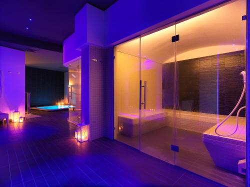 uma casa de banho com iluminação roxa, um chuveiro e uma banheira em DB Hotel Verona Airport And Congress em Caselle di Sommacampagna